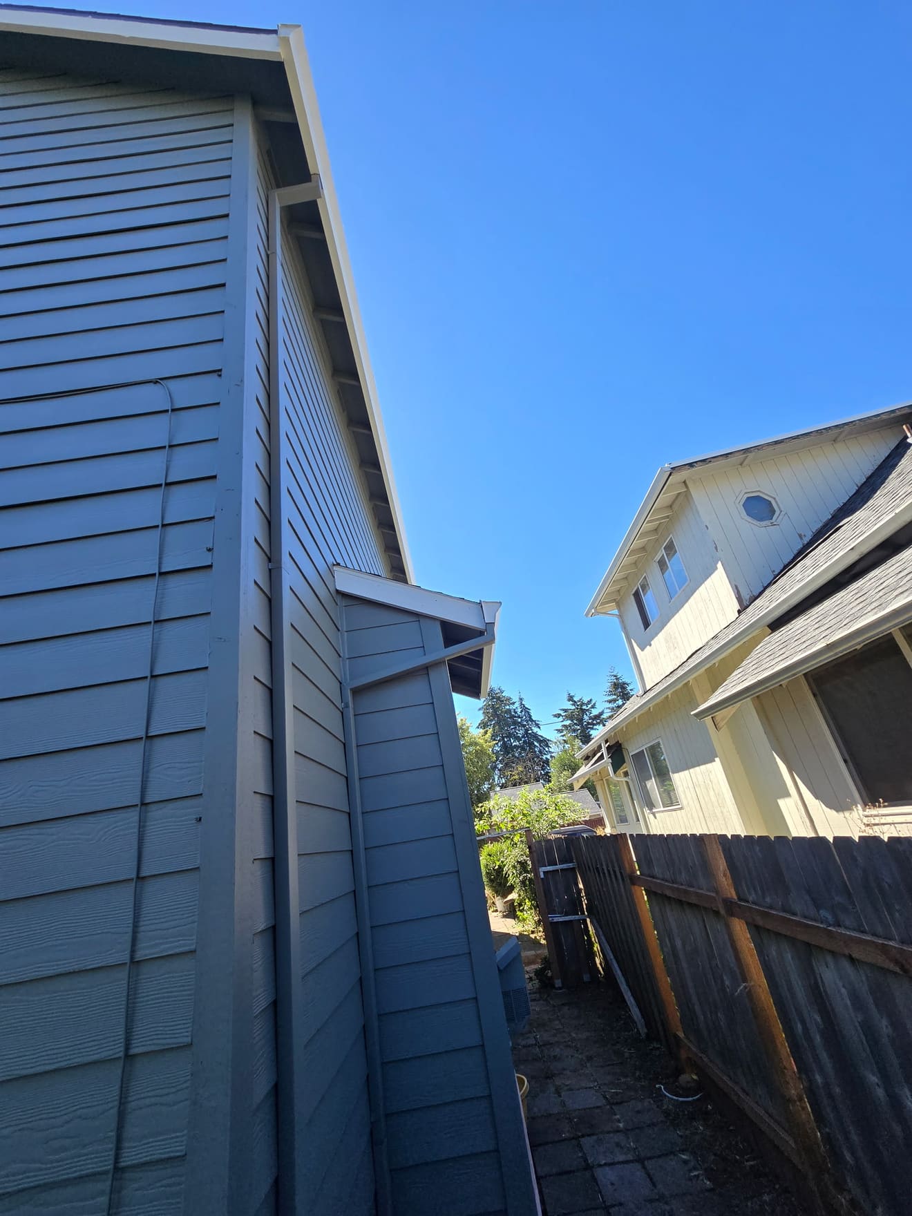 Same side elevation after painting — fresh blue siding with white trim