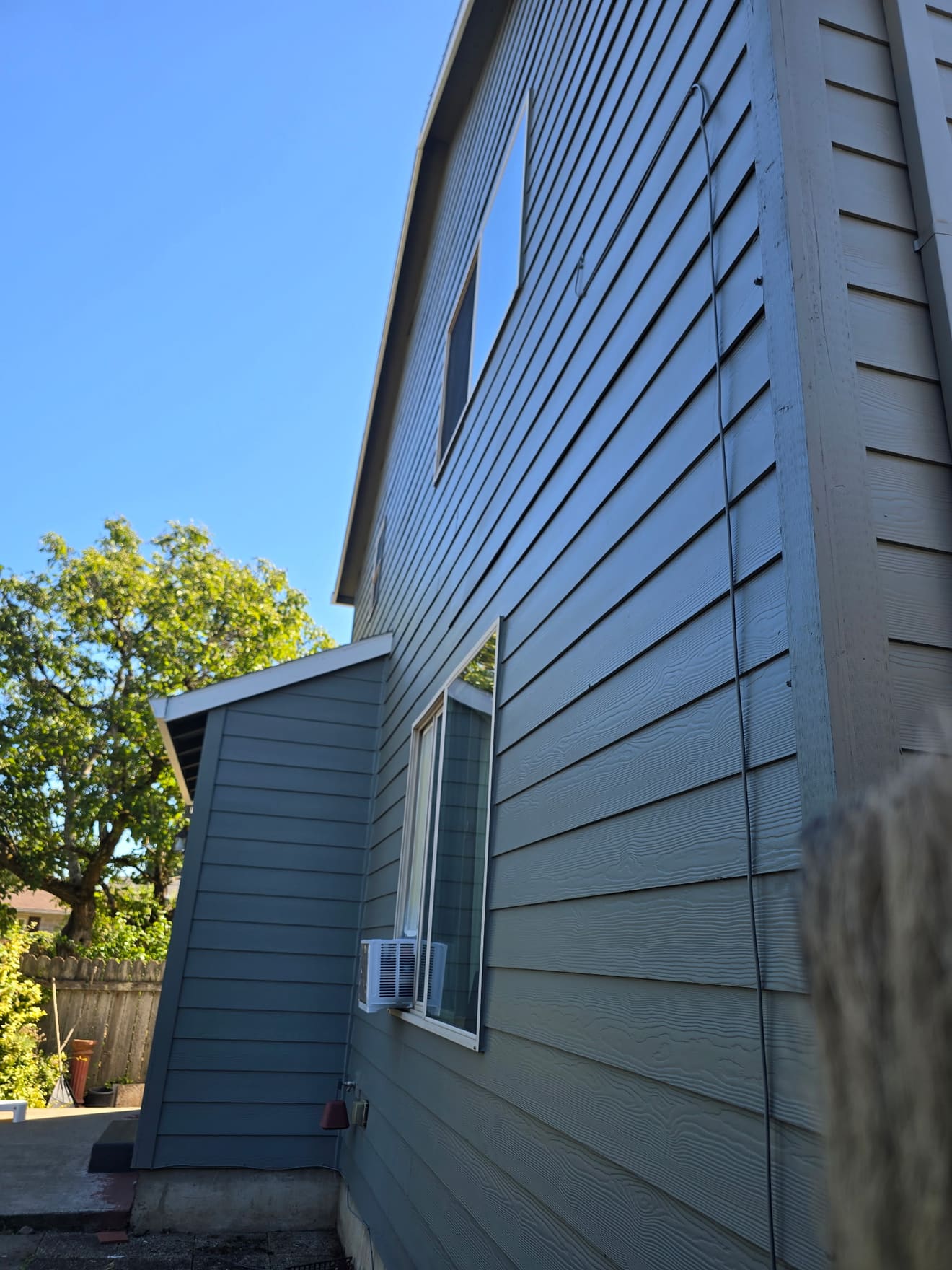Two-story side wall after repaint — smooth blue-gray siding