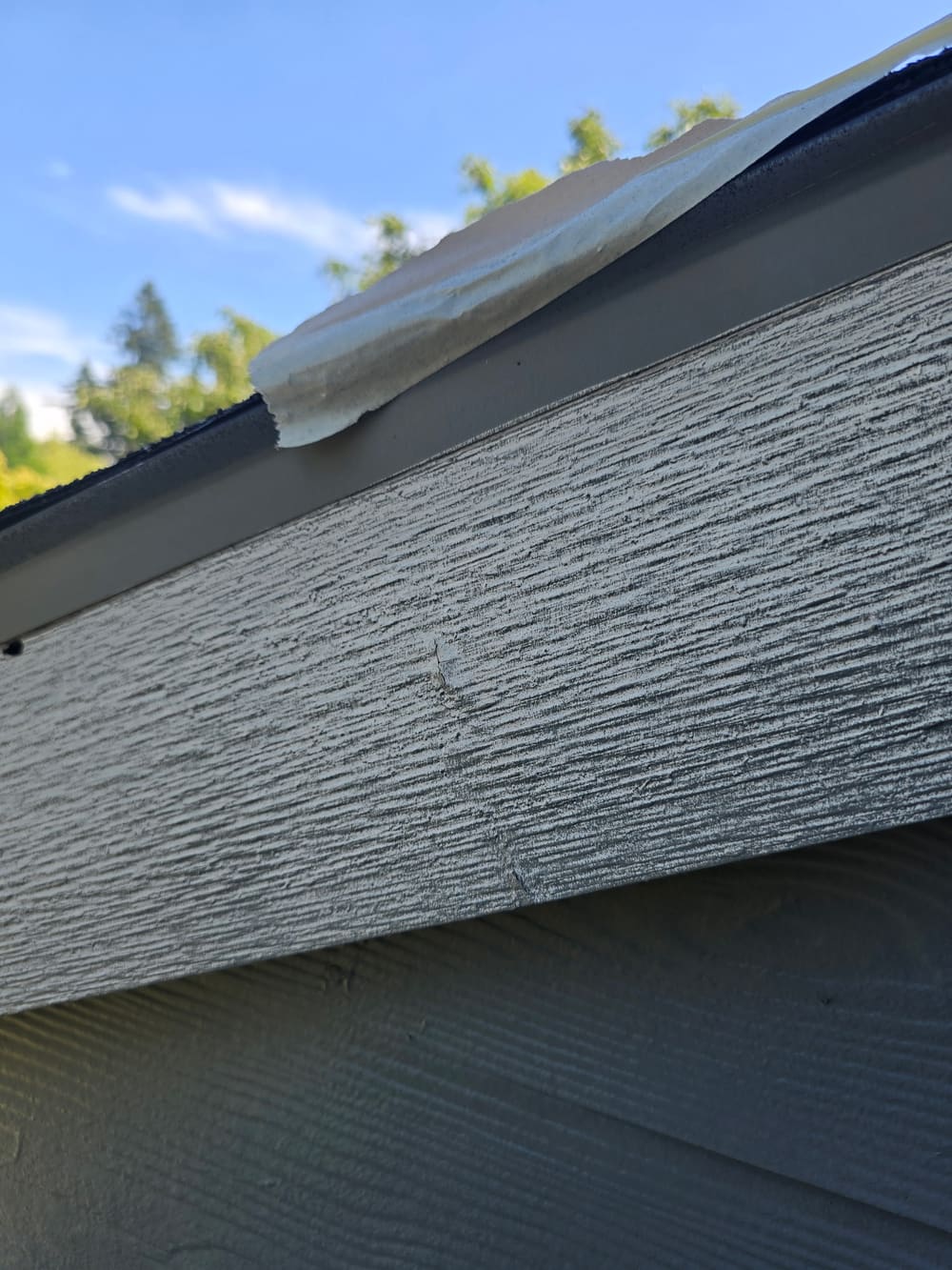 Roofline trim masked with plastic sheeting and primed before painting